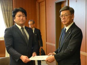 普天間第二小にCH53Eヘリから窓が落下した事故で、山本朋広防衛副大臣(左)に抗議文を手渡す翁長雄志知事=14日午後3時45分ごろ、防衛省