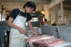 仕入れた豚肉を部位ごとに仕分するソーセージ職人の嶺井大地さん=19日、沖縄市中央