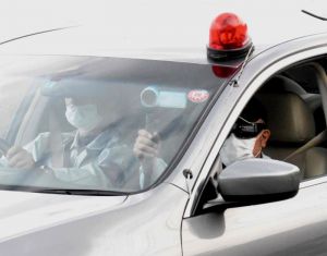 沿道で抗議する市民にビデオカメラを向ける警察官=9日午前8時すぎ、大宜味村喜如嘉