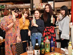 泡盛を手に撮影を行うインフルエンサーの女性参加者=18日、東京・大塚の飲食店「シスイドゥー」