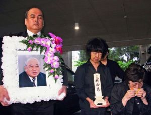 大田昌秀元沖縄県知事の出棺に際し、遺影や位牌(いはい)を掲げる親族=14日午後、沖縄県浦添市