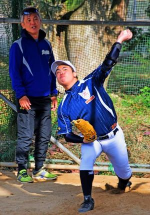 今年の初練習で投げ込みする田場一志さん(右)と指導に当たる藤井智監督=4日、西原高校グラウンド