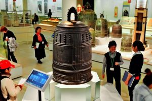 打音も聞くことができるようになった「万国津梁の鐘」(中央)。後方にも15世紀の鐘が並ぶ=24日、那覇市おもろまちの県立博物館・美術館