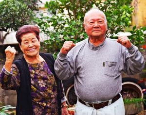 ガッツポーズする當山誠篤さん(右)と富美さん夫妻=15日、宜野湾市喜友名の自宅